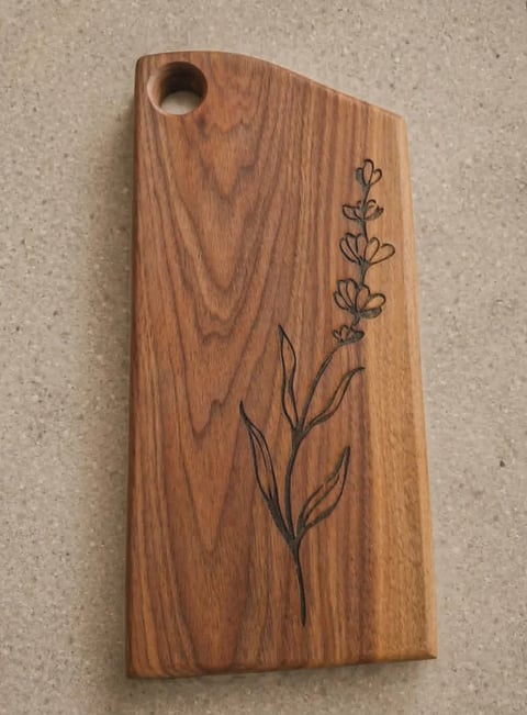 Wooden cutting board with hand-engraved botanical plant design and hanging hole